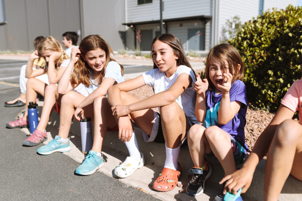 Children sitting together and smiling during a youth camp activity at Sessions Climbing + Fitness in El Paso, Texas.