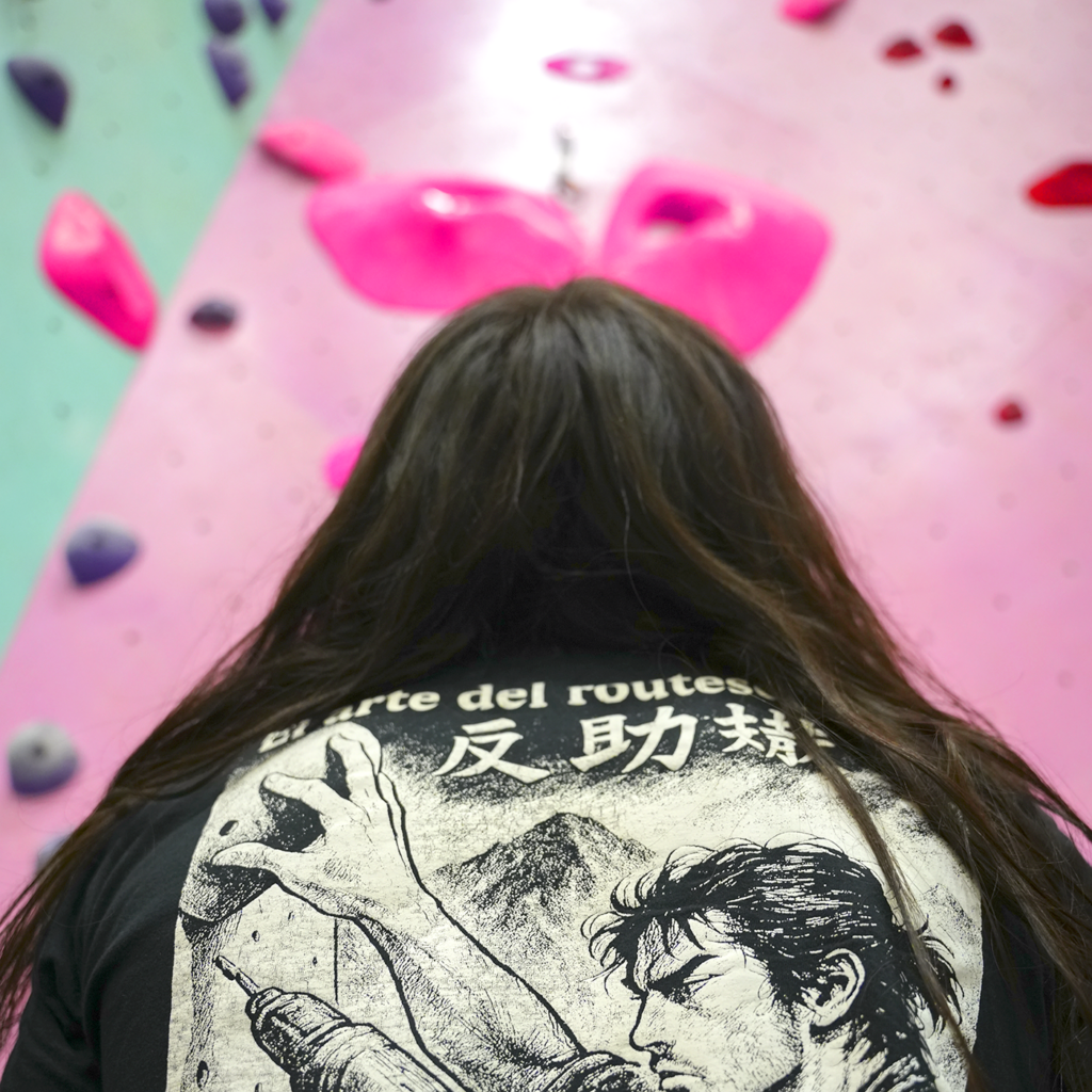 Climber standing beneath Antoine’s pink 5.13+ bounty route while looking up at the pink holds on the main lead wall at Sessions Climbing + Fitness
