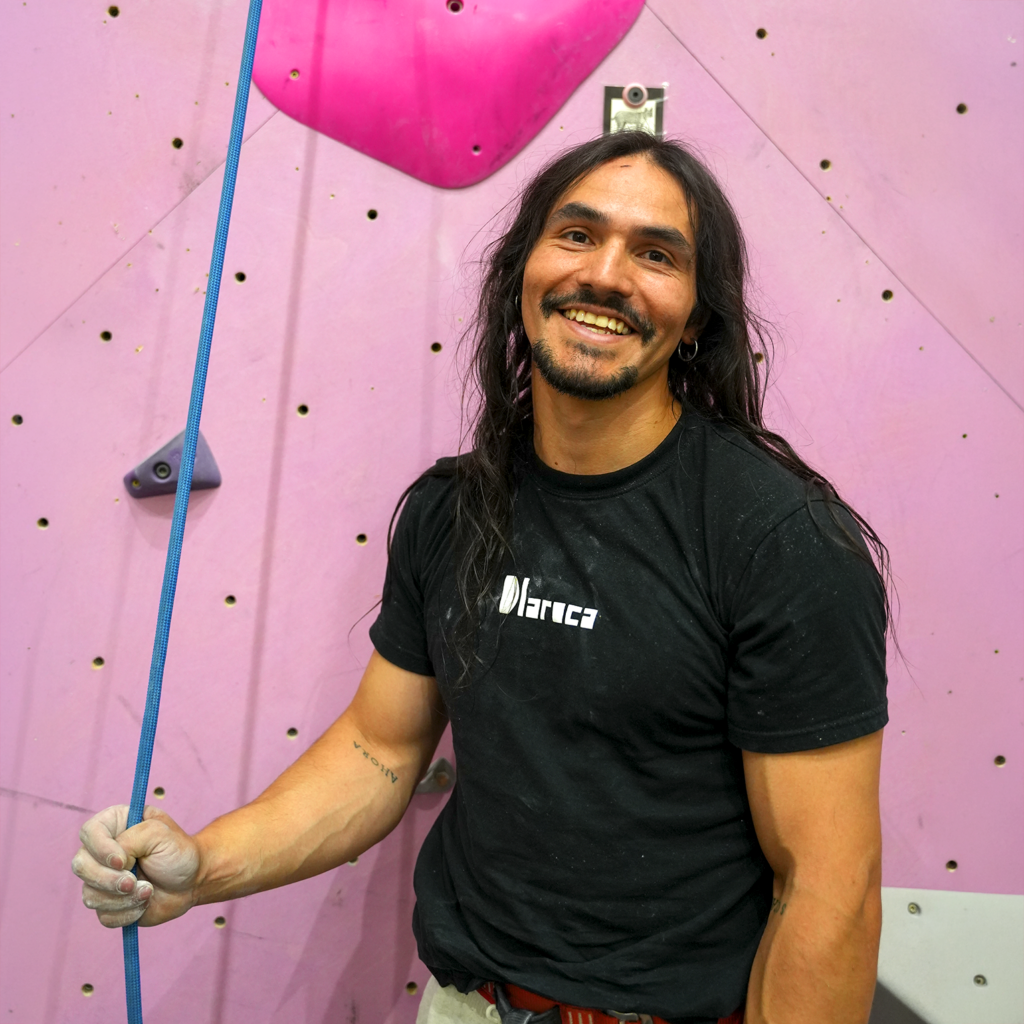 Guest routesetter Antoine standing beneath his pink 5.13+ bounty route on the main lead wall at Sessions Climbing + Fitness