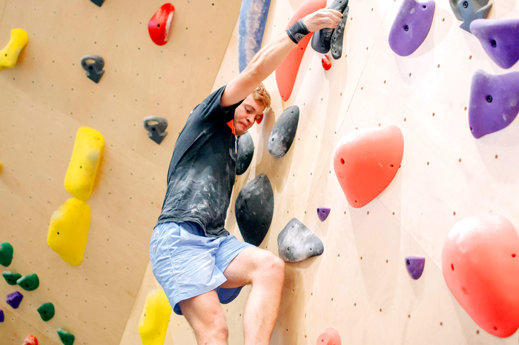 Climber ascending an indoor climbing wall during Sessions Summer Sendfest.